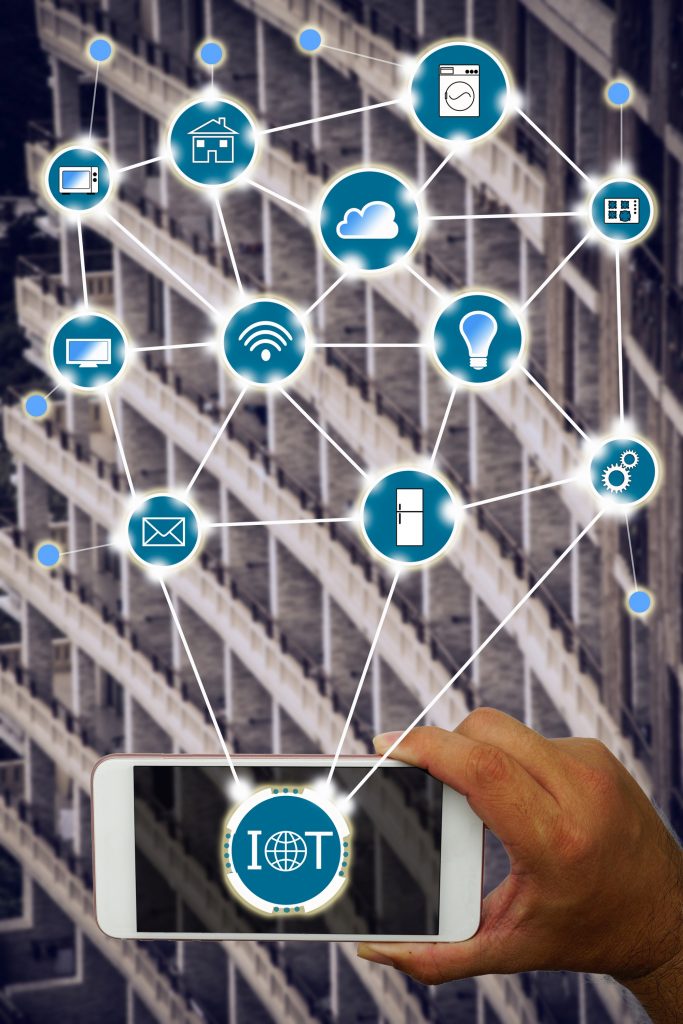 Internet of things (IOT) concept : Hand holding smartphone controlling various household equipment with building background. Smart home concept, Smart Building Concept.