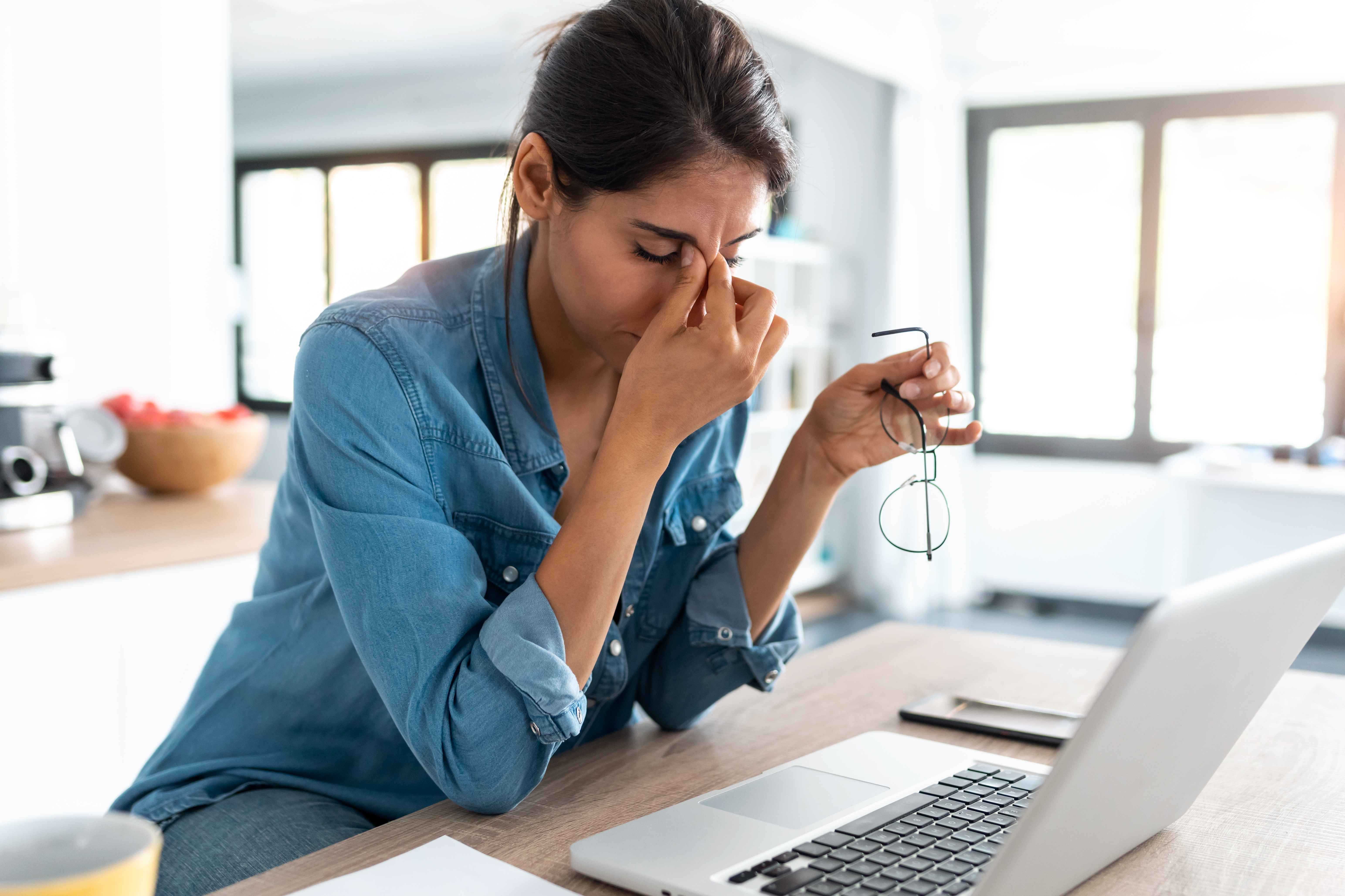 Shot of stressed business woman working from home on laptop looking worried, tired and overwhelmed.